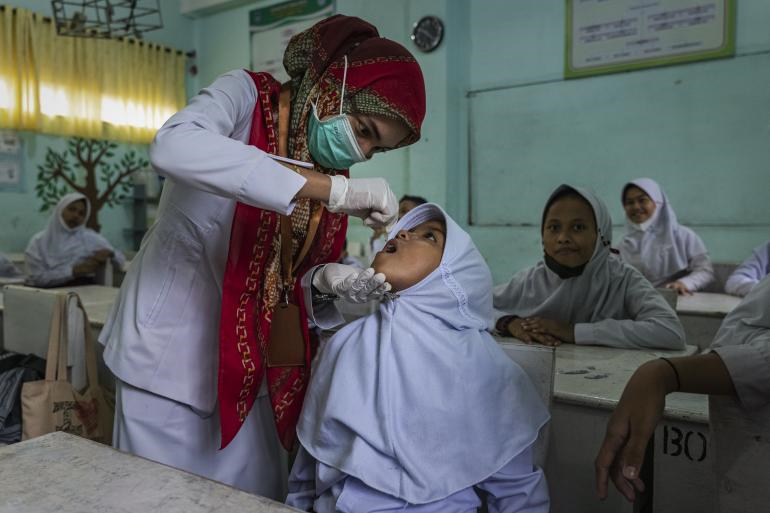 A health care worker immunizing a female student in Aceh.